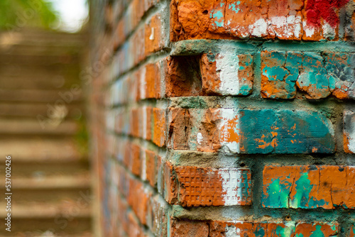 Close-up of a brick wall with remnants of color drawings and a concrete staircase in soft focus. Backdrop on the topic of a disadvantaged area and abandoned quarters of the city.