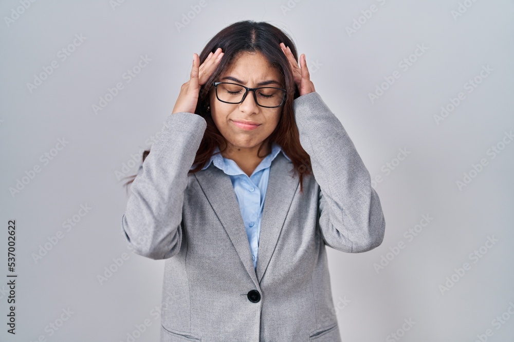 Hispanic young business woman wearing glasses with hand on head for pain in head because stress. suffering migraine. Hispanic young business woman wearing glasses with hand on head for pain in head because stress. suffering migraine.