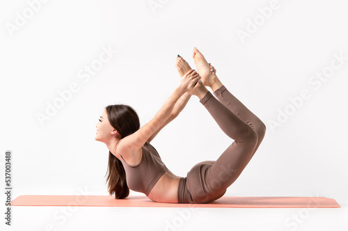 Pretty asian girl lying in yoga pose on a fitness mat. Excellent flexibility and plasticity of the body.