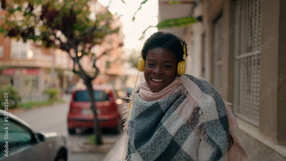 Young african american woman smiling confident listening to music at street