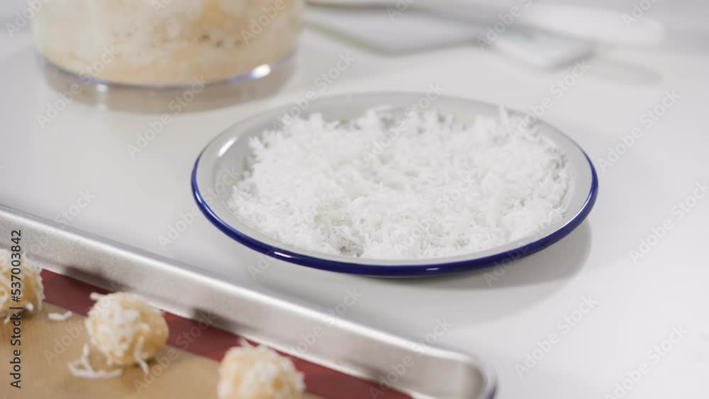 Scooping cookie dough into the baking sheet to bake coconut cookies. Scooping cookie dough into the baking sheet to bake coconut cookies.
