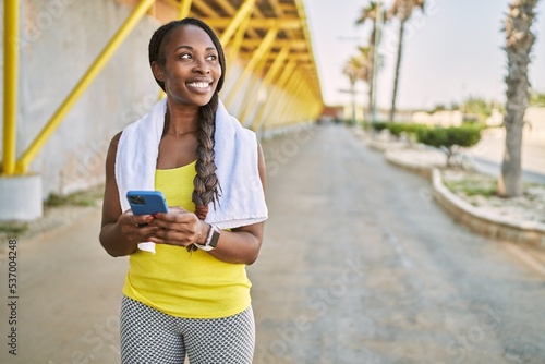 African american woman wearing sportswear using smartphone at street