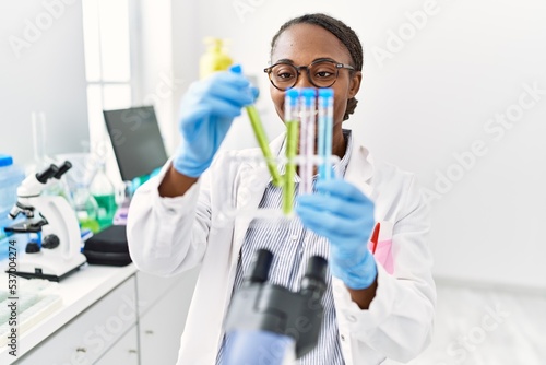 African american woman scientist holding test tubes at laboratory