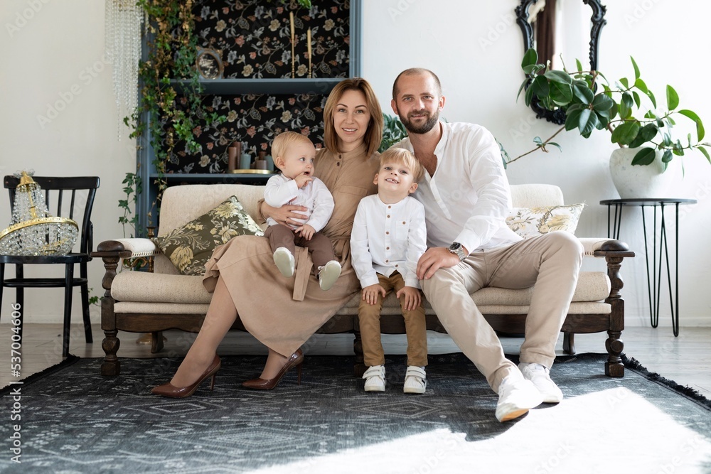 Obraz premium traditional family mom dad two boys sons with smiles looking at the camera sitting on the couch