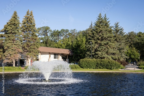 Beautiful shot of a fountain in a lake surrounded by trees in a park photo