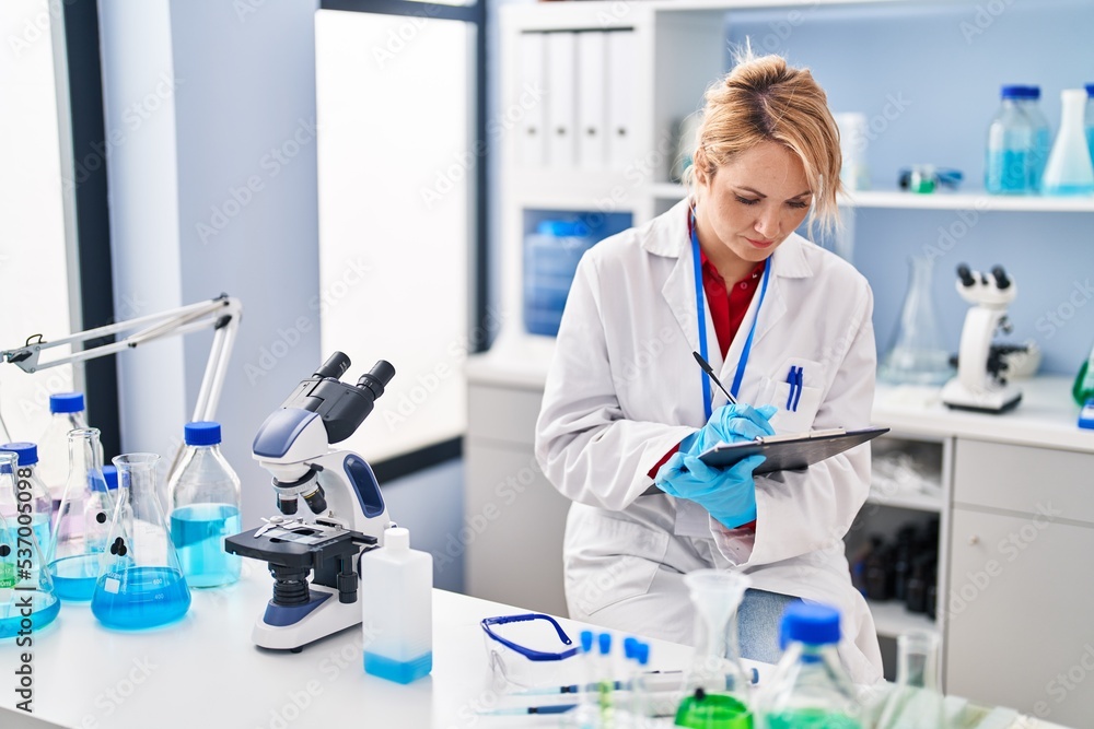 Young blonde woman scientist writing on document at laboratory Young blonde woman scientist writing on document at laboratory