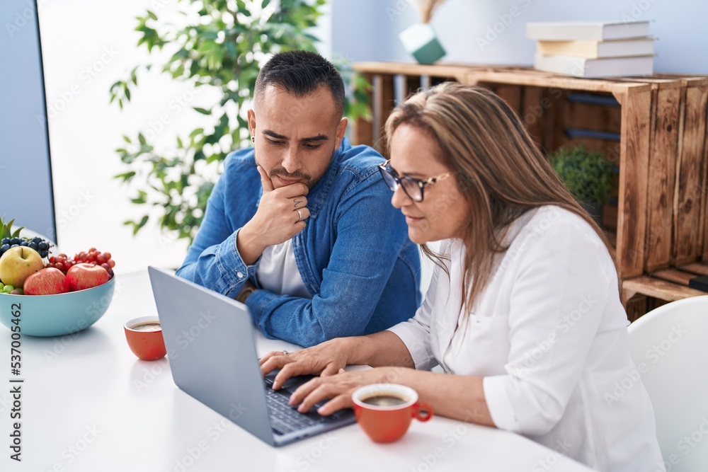 Man and woman mother and son drinking coffee using laptop at home Man and woman mother and son drinking coffee using laptop at home