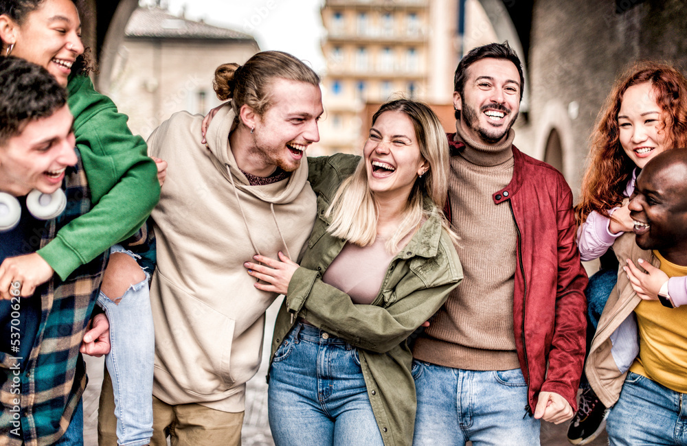 Happy multiracial smiling friends having fun together hugging and walking on the city street - Young millennial students having fun together - Youth lifestyle and friendship concept Happy multiracial smiling friends having fun together hugging and walking on the city street - Young millennial students having fun together - Youth lifestyle and friendship concept