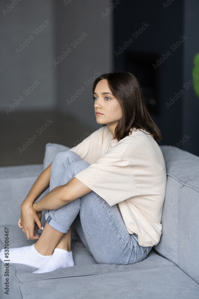 Naklejka premium Stressed young woman sitting on sofa at home