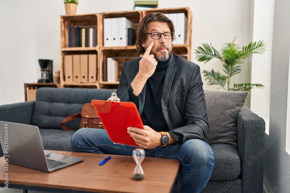 Handsome middle age man working at consultation office pointing to the eye watching you gesture, suspicious expression Handsome middle age man working at consultation office pointing to the eye watching you gesture, suspicious expression