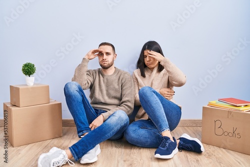 Young couple moving to a new home worried and stressed about a problem with hand on forehead, nervous and anxious for crisis