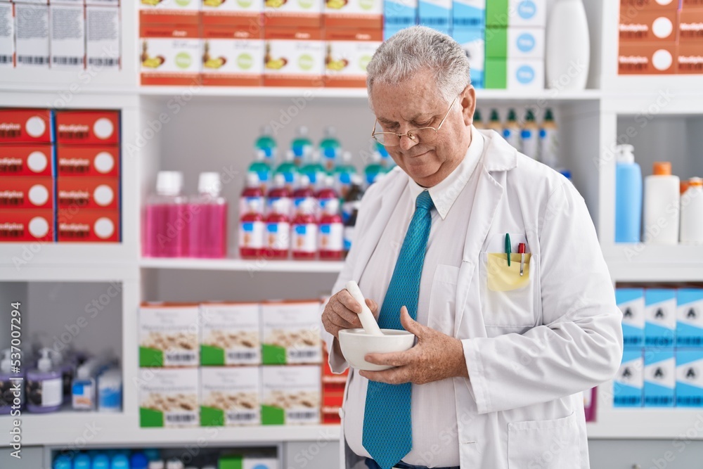 Middle age grey-haired man pharmacist smiling confident make mixture at pharmacy Middle age grey-haired man pharmacist smiling confident make mixture at pharmacy