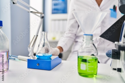 Young beautiful hispanic woman scientist weighing sample at laboratory
