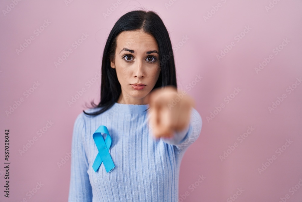 Hispanic woman wearing blue ribbon pointing with finger to the camera and to you, confident gesture looking serious Hispanic woman wearing blue ribbon pointing with finger to the camera and to you, confident gesture looking serious