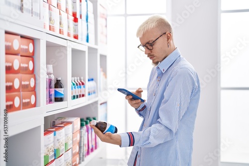 Young caucasian man customer making photo to medication bottle at pharmacy