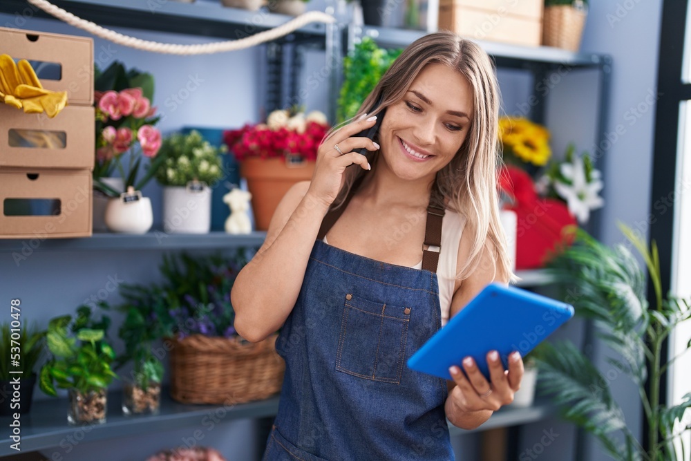 Young caucasian woman florist talking on smartphone using touchpad at florist Young caucasian woman florist talking on smartphone using touchpad at florist
