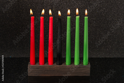 Kwanzaa festival concept with seven candles red, black and green in candlestick on black background, copy space photo