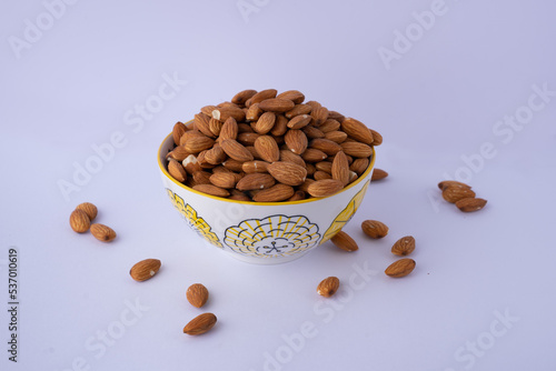 Raw almonds in a bowl on white background