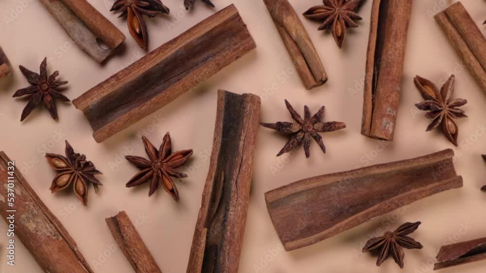 Rotation background with cinnamon sticks and anise stars on a beige background, cozy food, spicy trendy background Rotation background with cinnamon sticks and anise stars on a beige background, cozy food, spicy trendy background