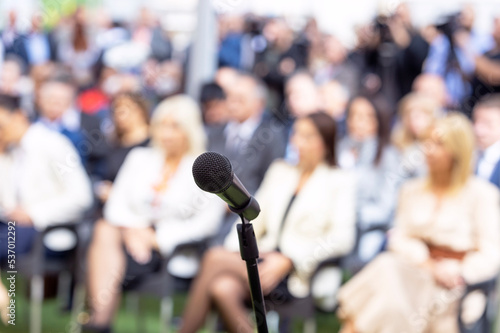 Business conference event or corporate presentation, microphone in the focus, blurred audience in the background