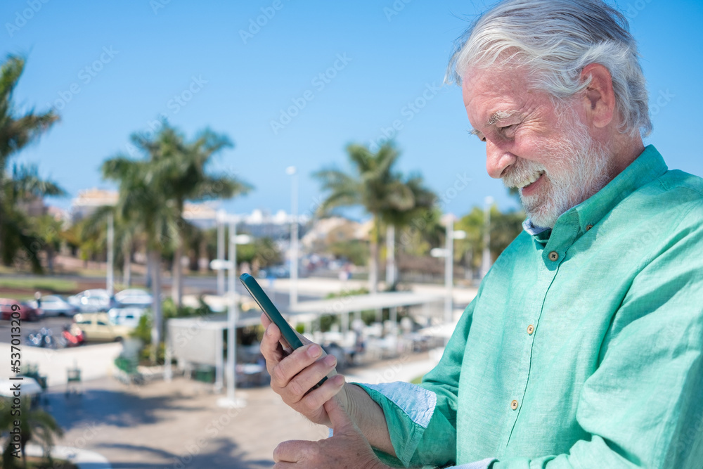 Handsome senior bearded man smiling while using mobile phone in outdoor Handsome senior bearded man smiling while using mobile phone in outdoor