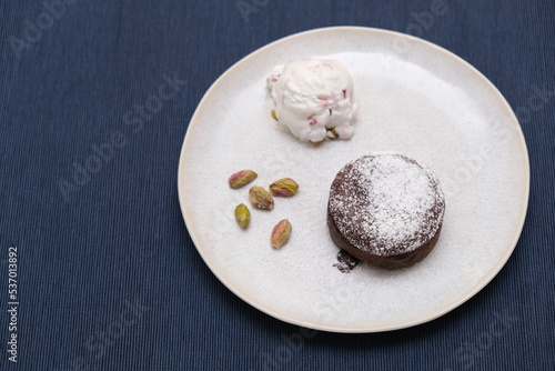 Brown chocolate soufflé with ice cream and pistachios decoration on a plate