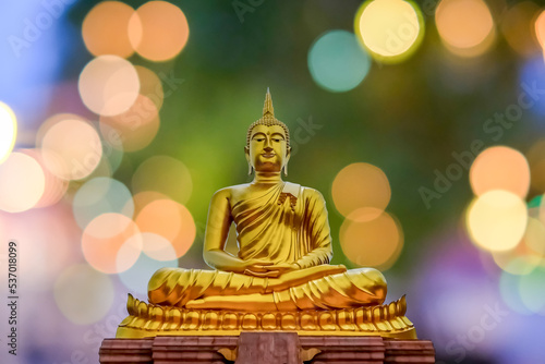 Close up golden Buddha meditation statue with light bokeh 