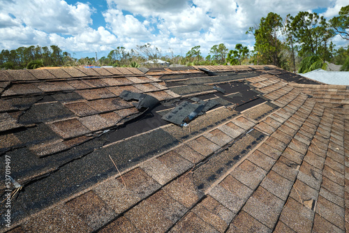 Fotografia Damaged house roof with missing shingles after hurricane Ian in Florida