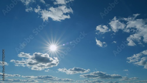 Clouds moves in the blue sky. Beautiful sky cloudy behind shining sun rays and eventually breaking through cloud mass. Timelapse.