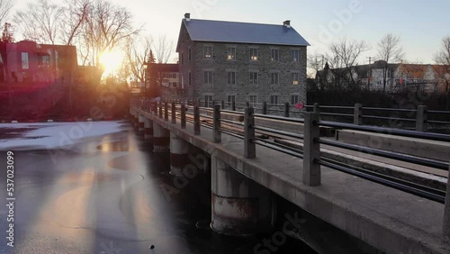 Golden sunshine in late fall early winter with the beautiful Watson's mill. Showcasing the beautiful mill, dam, freezing rideau river with ice forming.  photo