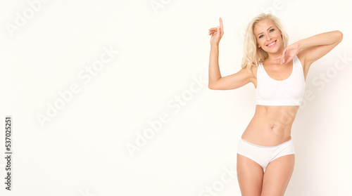 Cheerful woman in underwear on white wall.