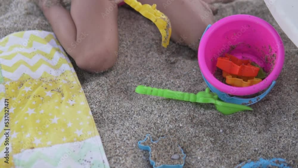 Close-up, a child playing in the sand with a shovel on the beach. Close-up, a child playing in the sand with a shovel on the beach.