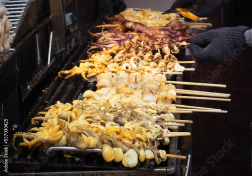 Fresh squid skewered on a charcoal grill ready to eat for grilled seafood barbecue.