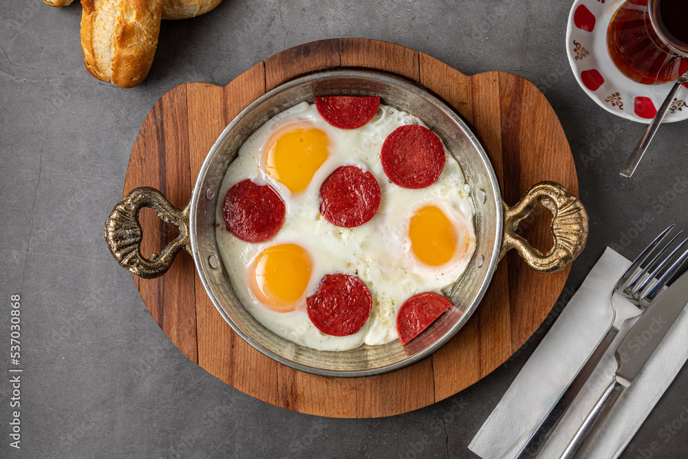 fried eggs with turkish sausage with bread and tea on dark stone table fried eggs with turkish sausage with bread and tea on dark stone table