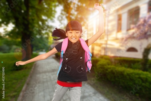 Happy small school child running on street.