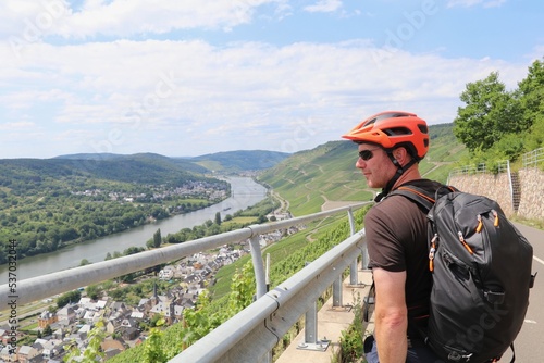 Foto Man with bright orange bike helmet looking out over a panoramic view of the Mose