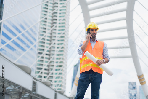 Man engineer standing on construction site. construction manager using walkie talkie. Engineer working on outdoor project and talking on phone