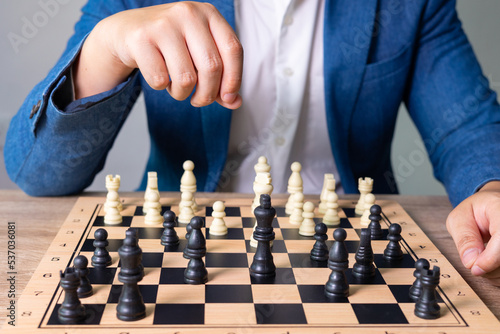 Close up shot of businessman's hand picking the chess piece to kill the enemy king to win the game. It shows concept of competition with strategic business planning of teamwork for winning the battle.