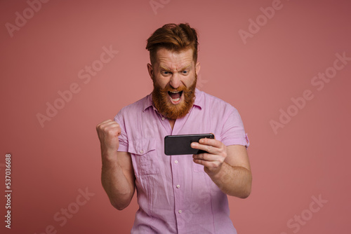 Ginger white man making winner gesture while using mobile phone © Drobot Dean