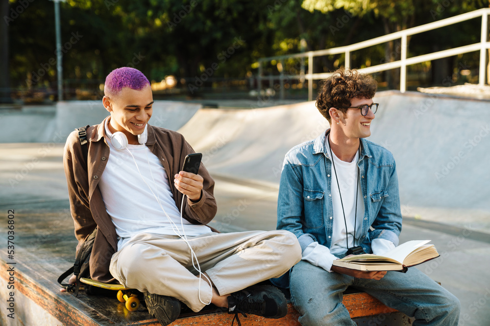 Naklejka premium Two young handsome stylish smiling boys sitting togehter