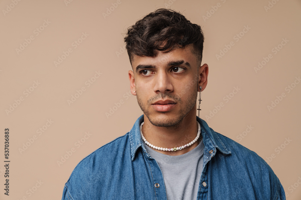Young handsome stylish man with piercing in necklace looking aside Young handsome stylish man with piercing in necklace looking aside