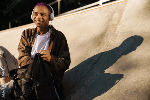 Photos Young handsome smiling stylish boy in headphones rummaging in backpack