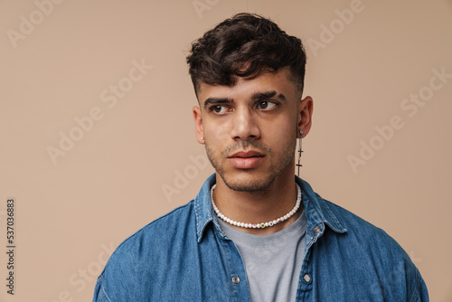 Young handsome stylish man with piercing in necklace looking aside © Drobot Dean