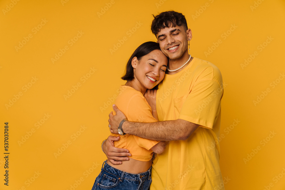 Young multiracial couple hugging while smiling together Young multiracial couple hugging while smiling together