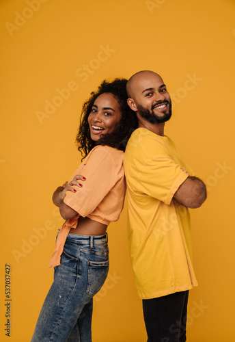 Black young man and woman smiling while standing back to back