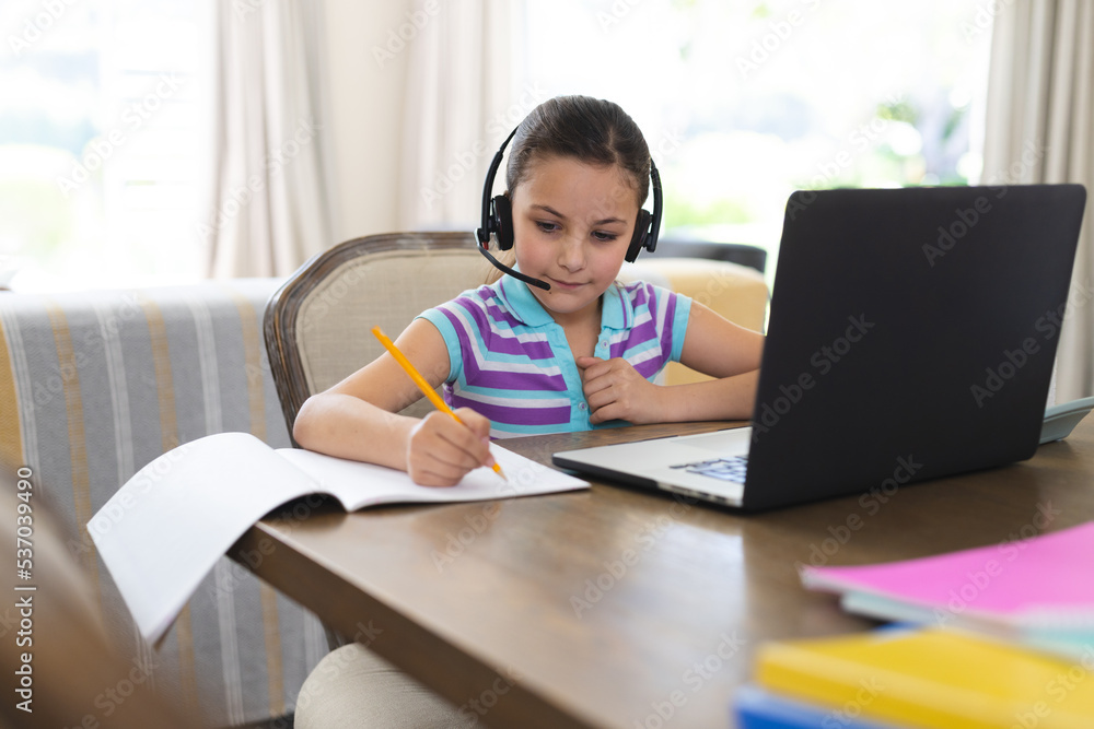 Caucasian girl learning and using laptop and headphones in living room Caucasian girl learning and using laptop and headphones in living room