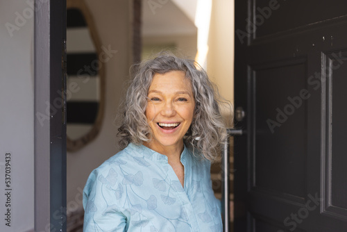Happy african senior caucasian women opening door and welcoming somebody