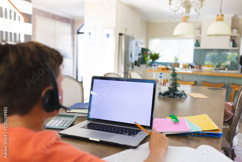 Caucasian boy using laptop with copy space and headphones at home photo