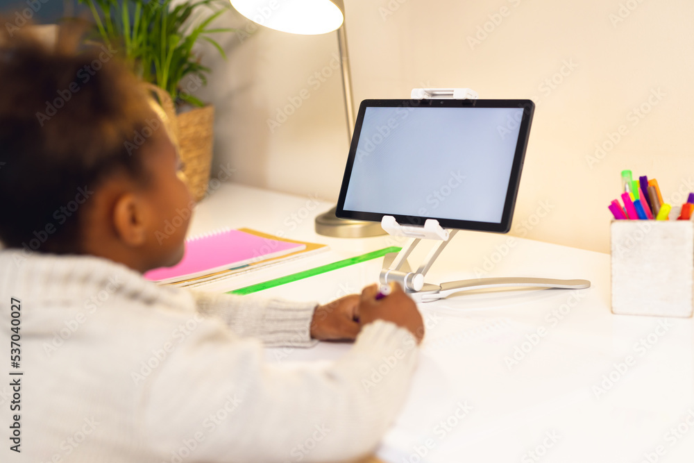 Happy african american girl learning, using tablet with copy at home Happy african american girl learning, using tablet with copy at home