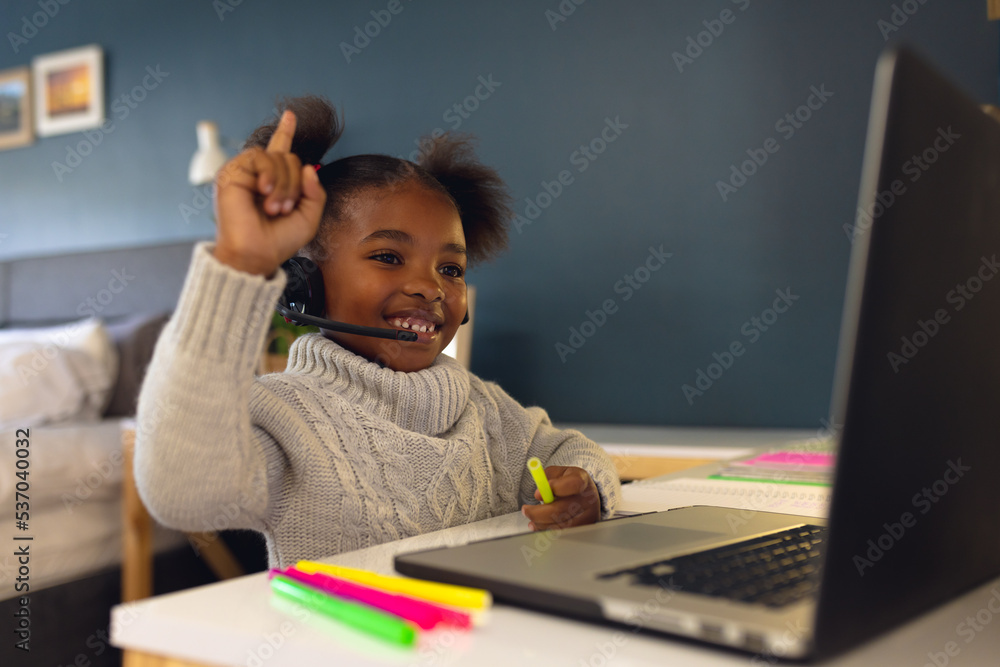 Happy african american girl learning, using laptop and headphone at home Happy african american girl learning, using laptop and headphone at home